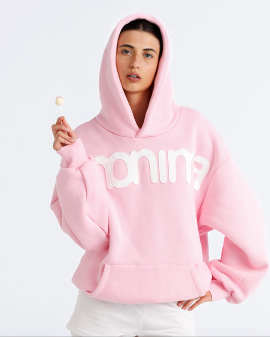 Person wearing a pink hoodie with text, holding a popsicle against a white background