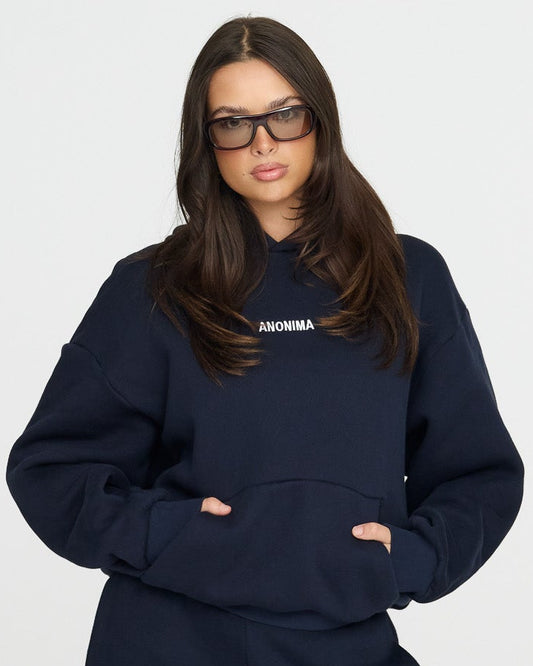 Person wearing a navy tracksuit with sunglasses on a white background