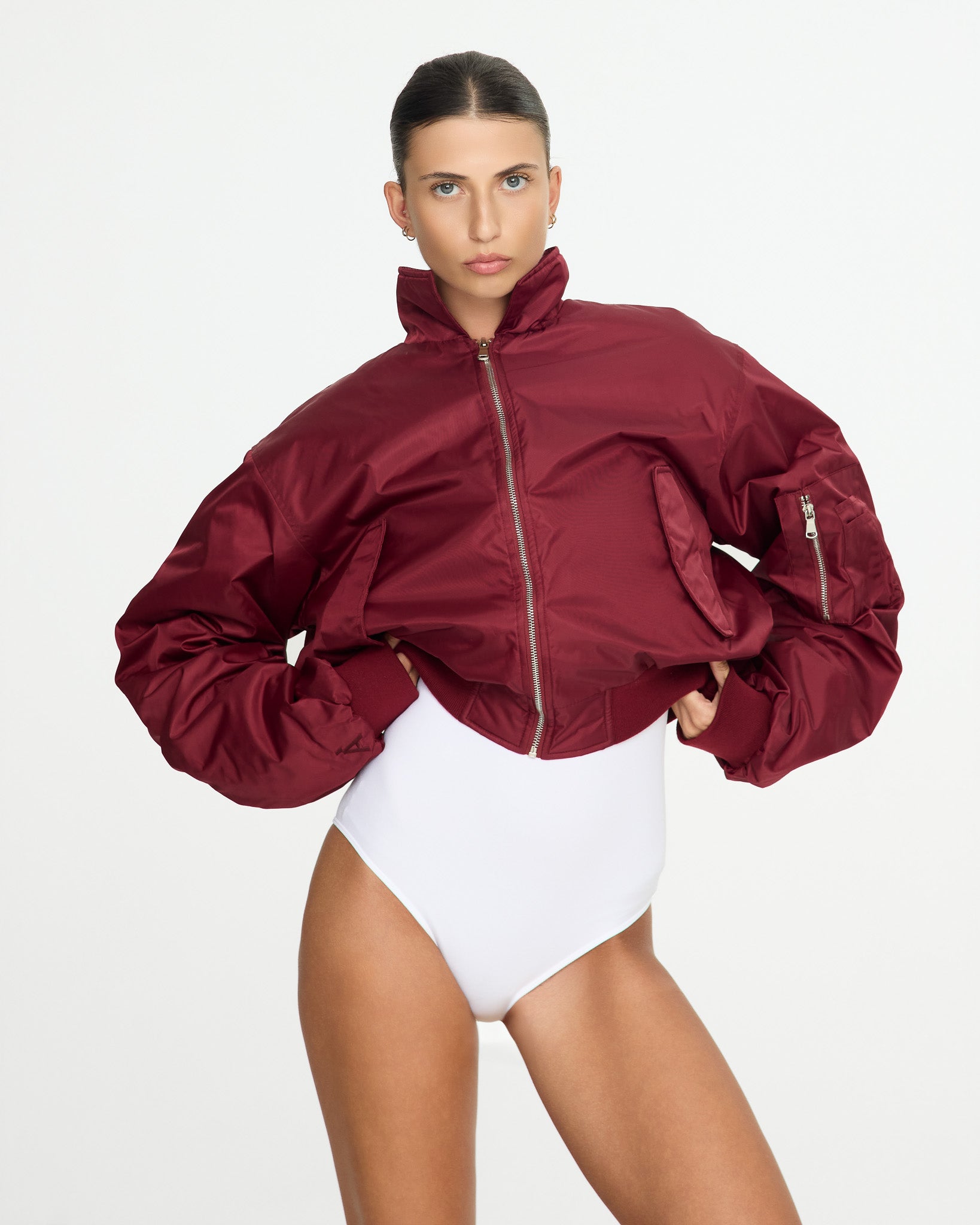 Person wearing a burgundy jacket and white swimsuit on a plain background