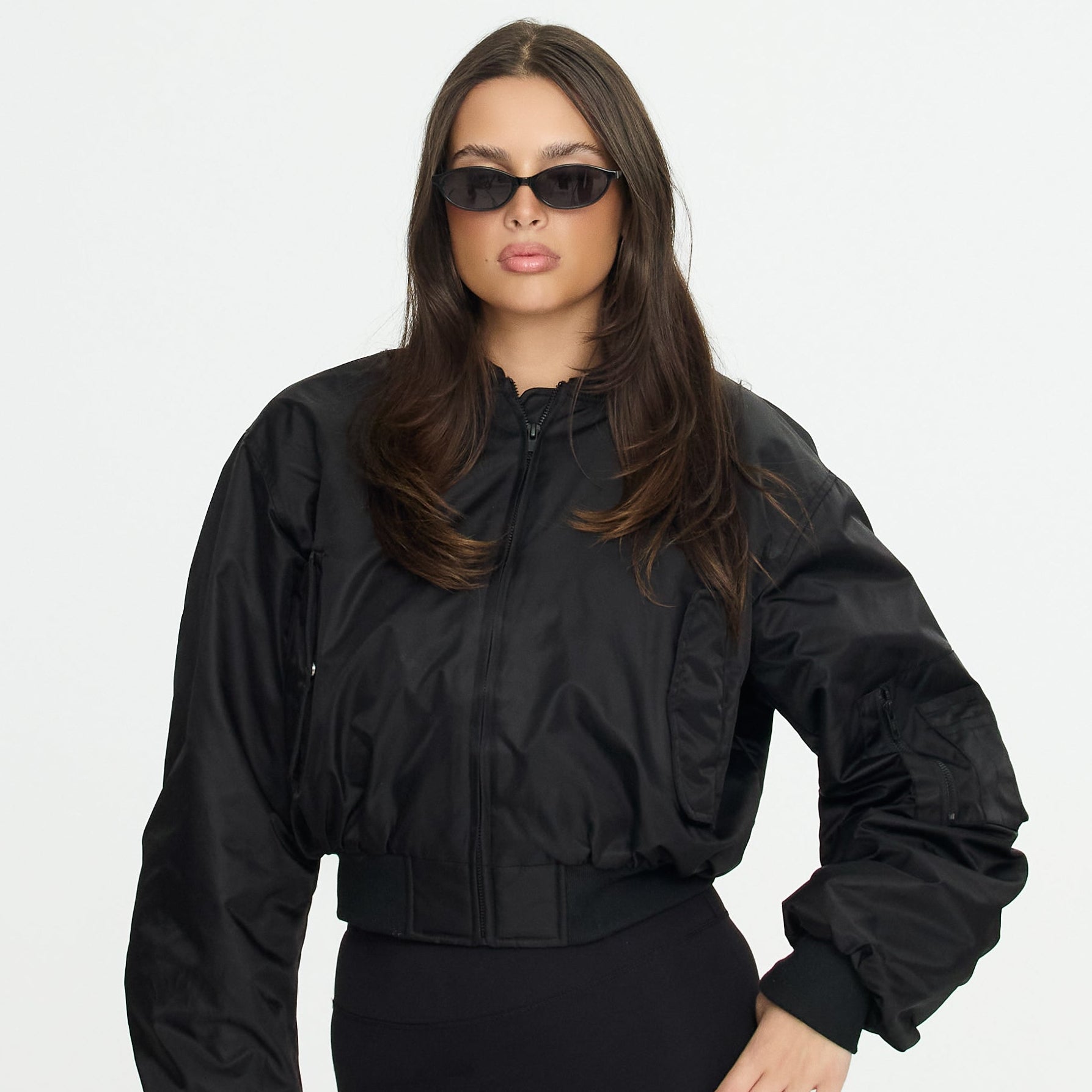 Woman wearing a black jacket and sunglasses on a white background