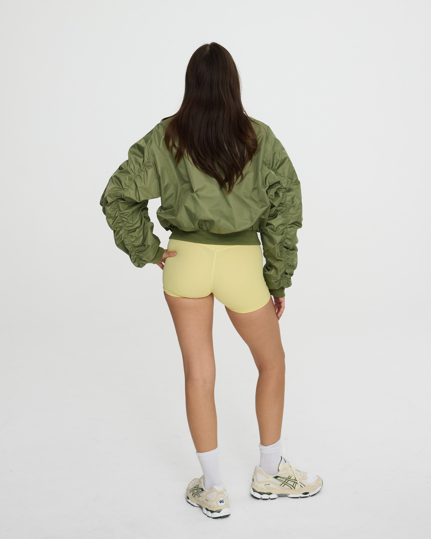 Person wearing a green jacket and yellow shorts on a white background