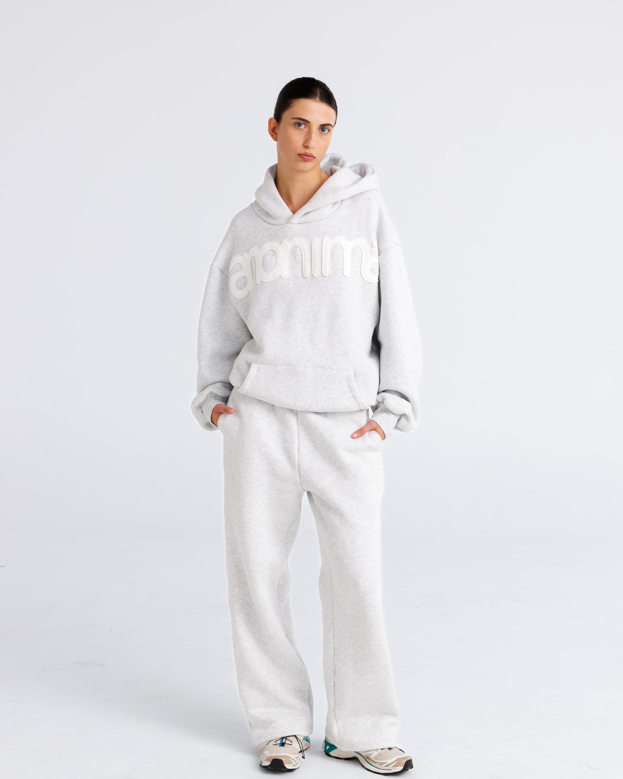 Person wearing a grey hoodie with branding on a light gray background