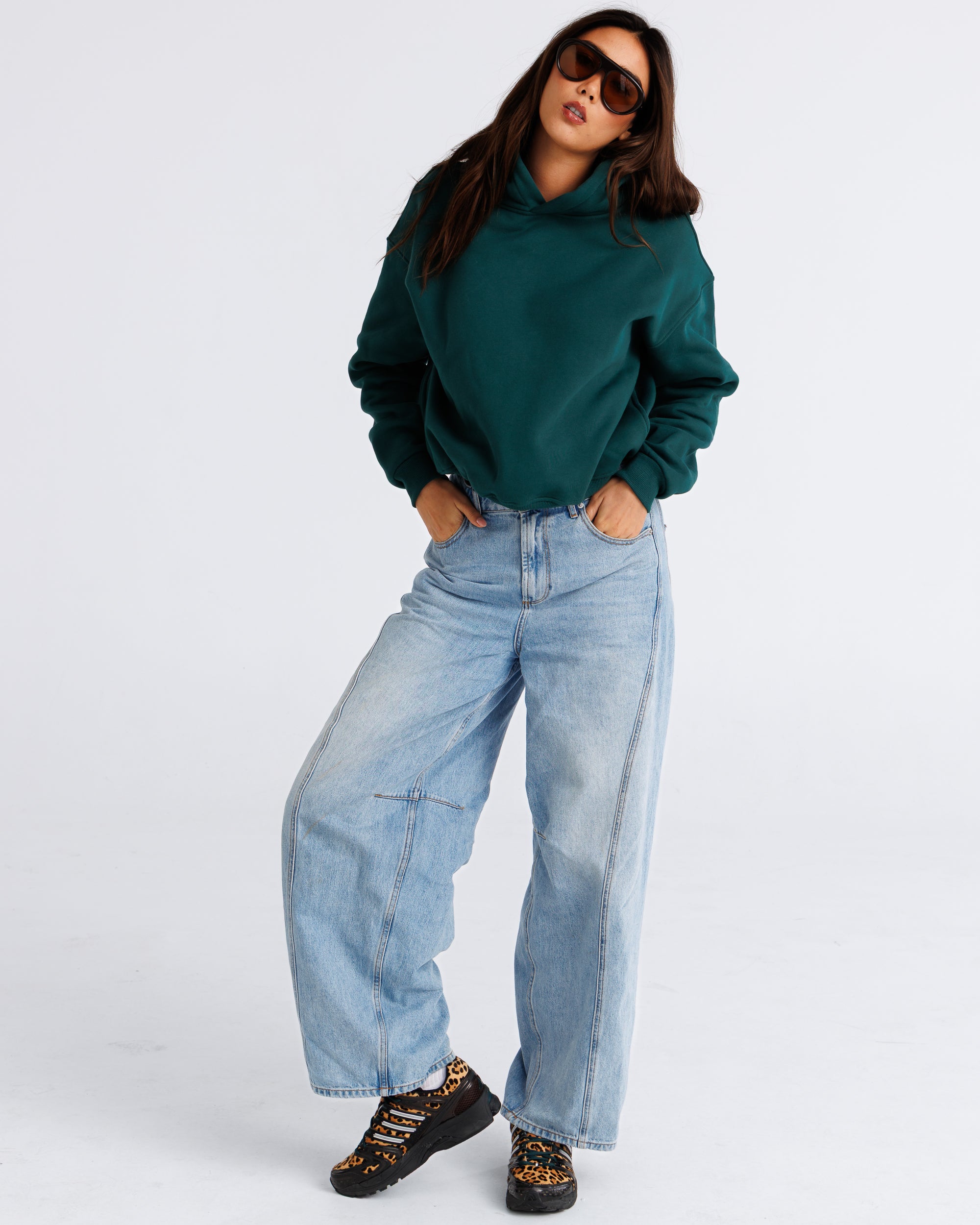Person wearing a green sweater and blue jeans on a white background