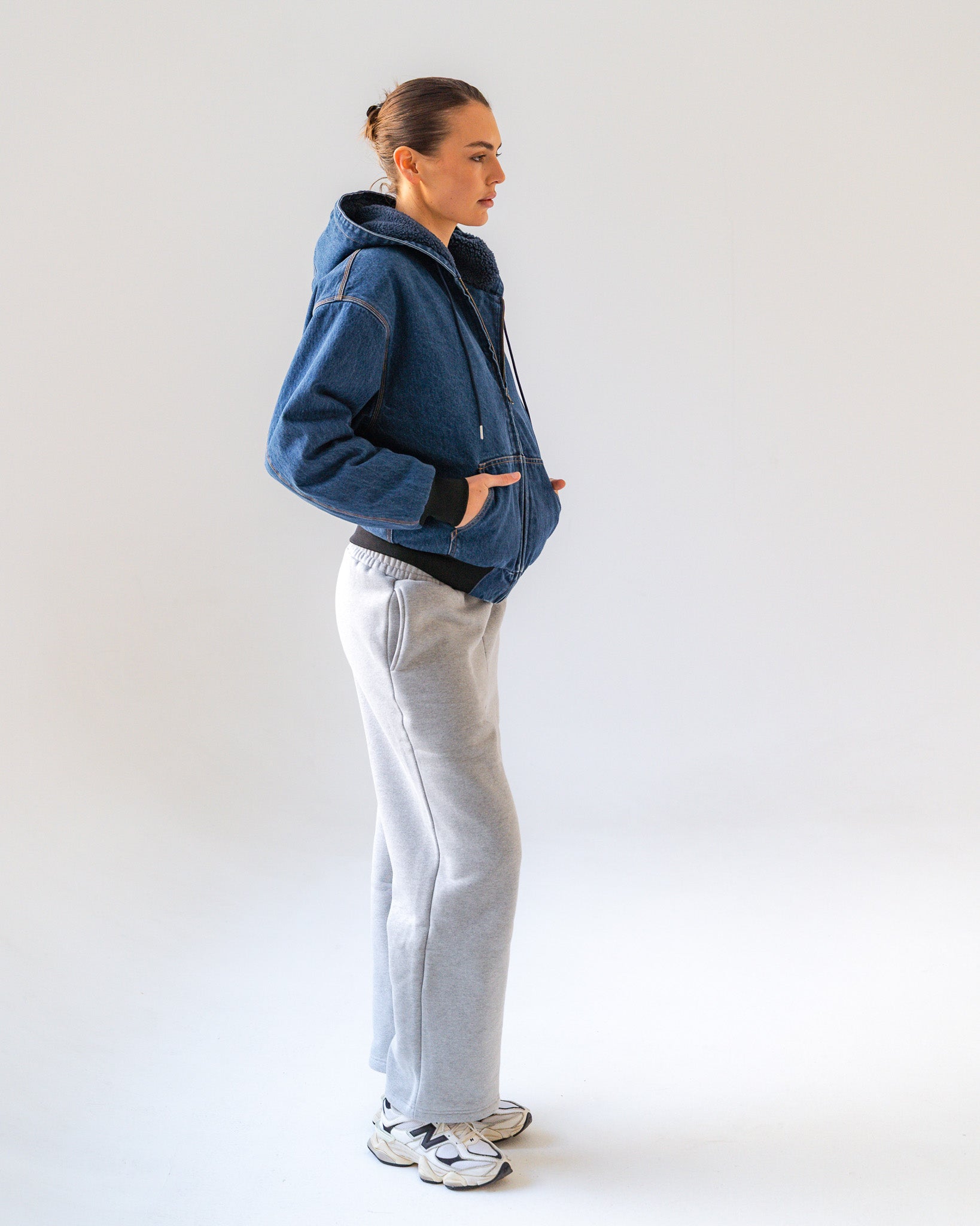 Person wearing a blue jacket and gray pants on a white background