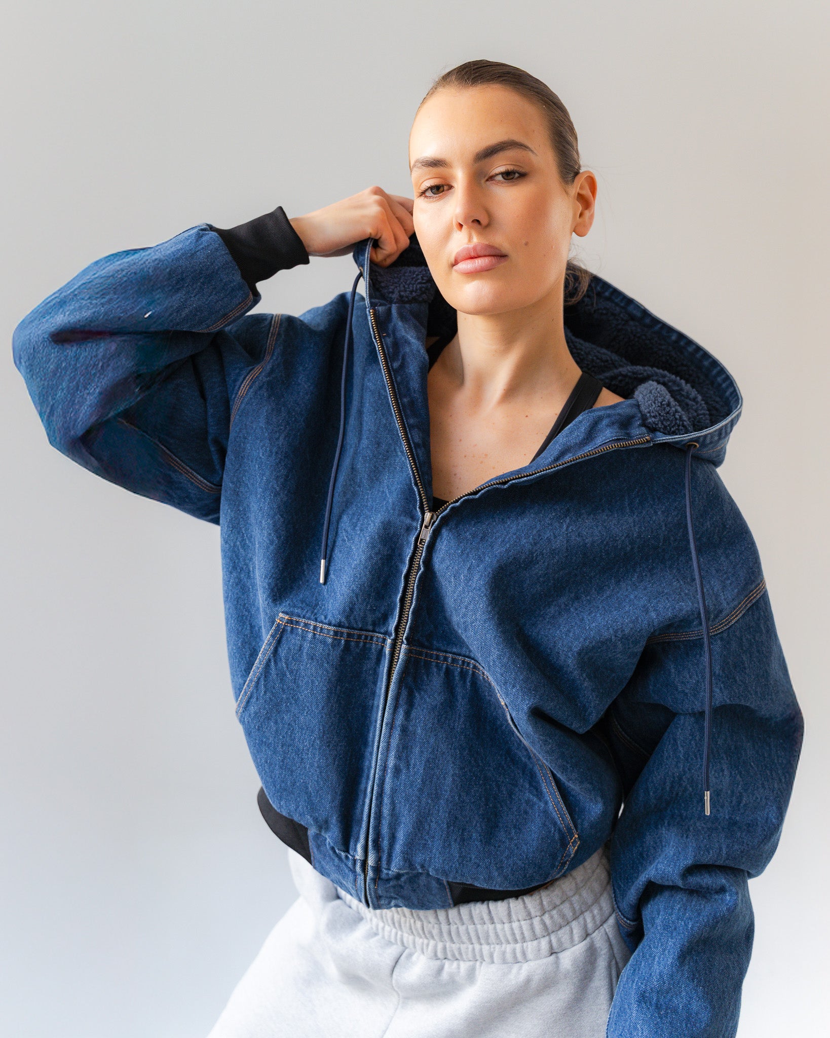 Person wearing a blue denim jacket against a plain background