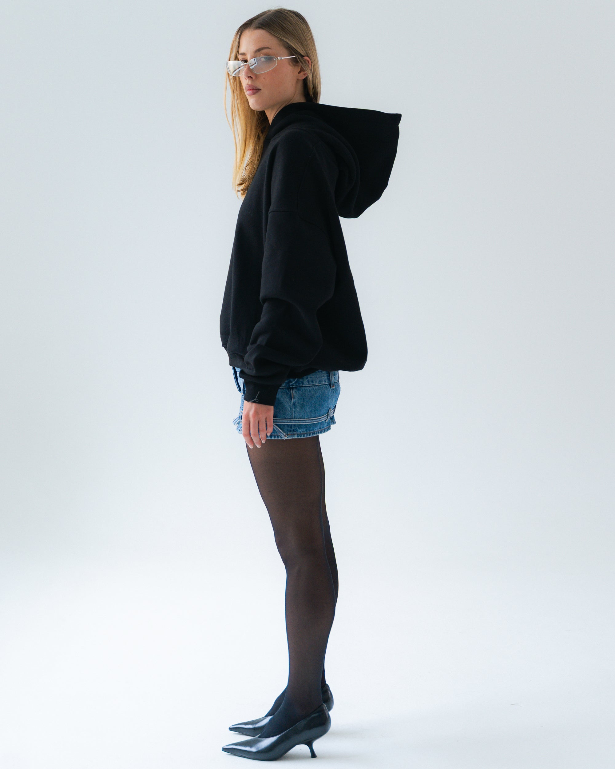 Woman wearing a black hoodie and denim shorts on a white background