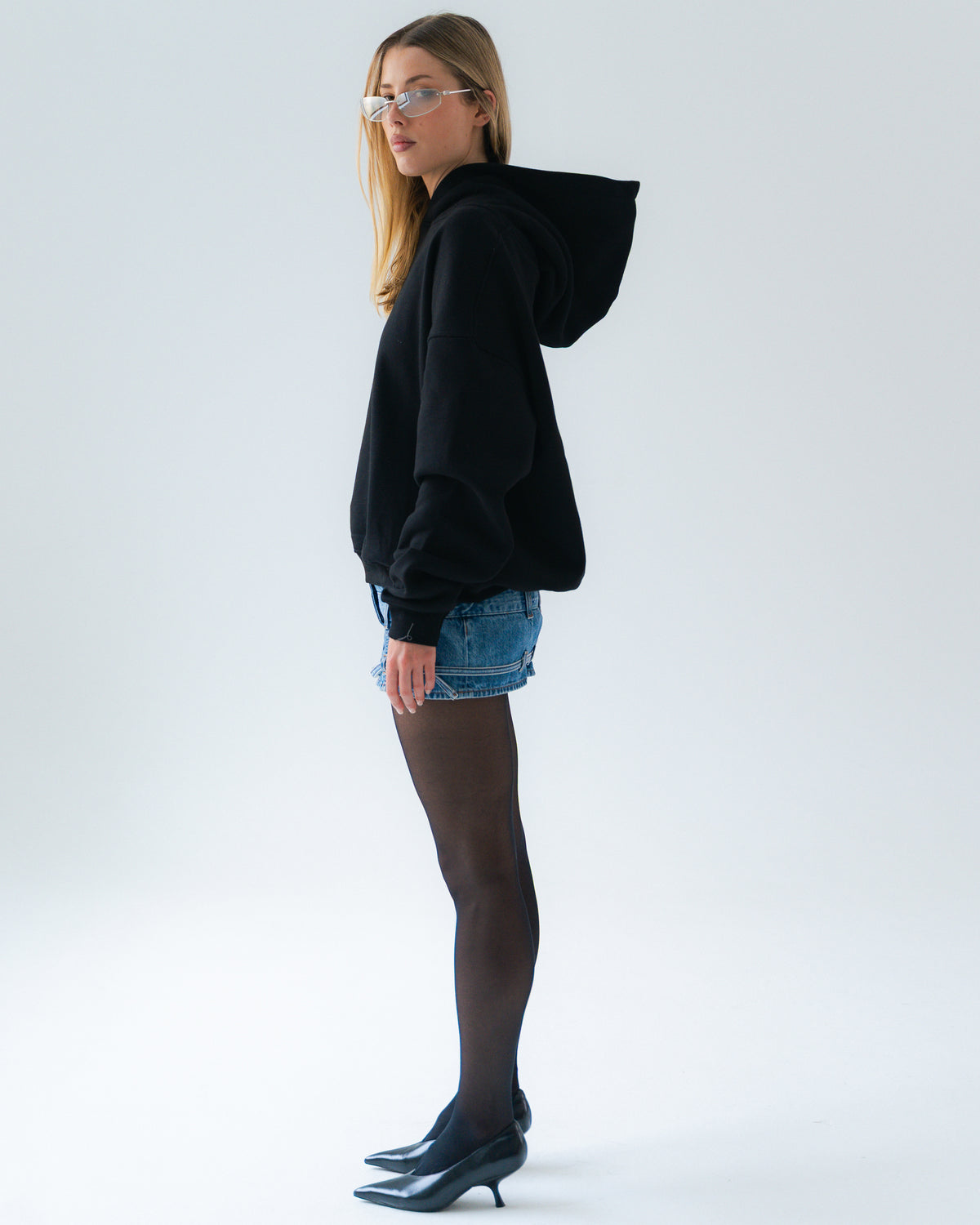 Woman wearing a black hoodie and denim shorts on a white background