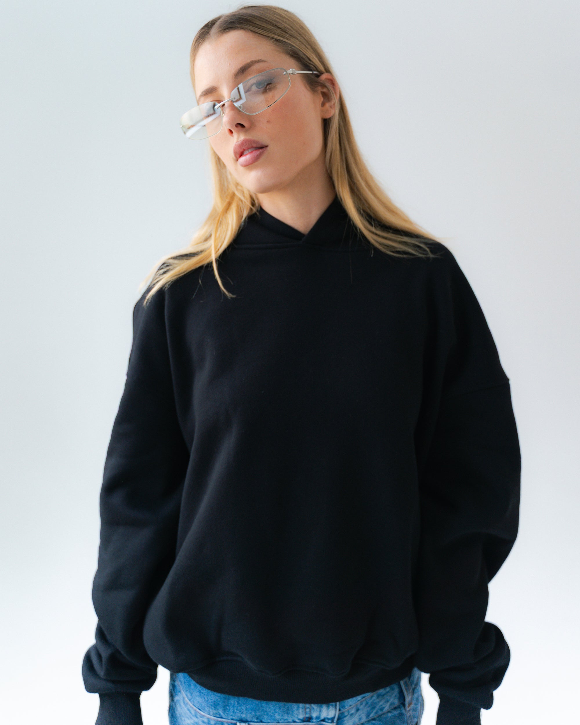 Person wearing a black turtleneck sweater and blue jeans against a plain background